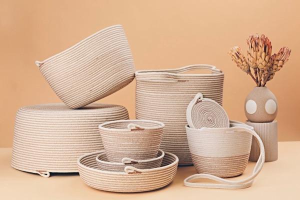 Woven baskets and a vase with dried flowers on a tan background.